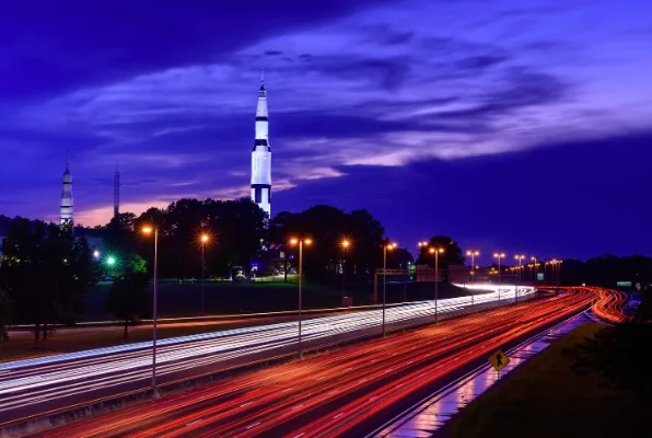 Saturn V rocket at the U.S. Space & Rocket Center in Huntsville, Alabama at sunset with highway light trails — the Rocket City's aerospace heritage meets modern logistics infrastructure